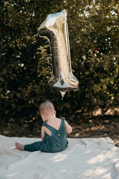 a baby sitting on the ground with a balloon in the air