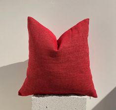 a red pillow sitting on top of a cement block