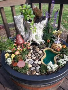 a potted planter filled with lots of plants and small rocks on top of a wooden deck