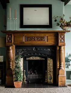 a fireplace in a living room with a painting on the wall and potted plants