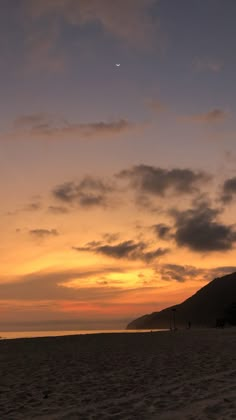 the sun is setting at the beach with people on it