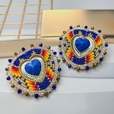 two pairs of colorful beaded earrings sitting on top of a white table next to each other