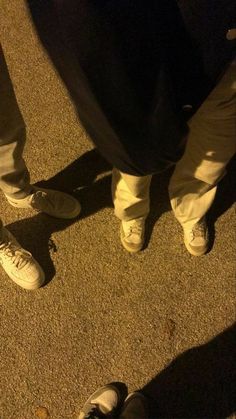 two people standing next to each other with shoes on the ground in front of them