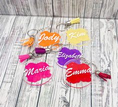 six personalized key chains with tassels and name tags on them sitting on a white wooden surface