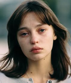 a close up of a person wearing a sweater and looking at the camera with a serious look on her face