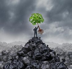 a man standing on top of a pile of garbage holding a tree