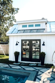 a small white house with a pool in the yard and sun shining on it's windows