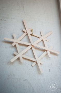 a snowflake made out of popsicle sticks sitting on top of a white wall