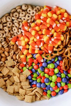 a bowl filled with candy corn, pretzels, and other cereals in it