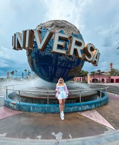 a woman posing in front of the universal studios sign