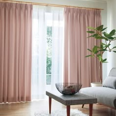 a living room with pink drapes and a white rug on the hardwood flooring