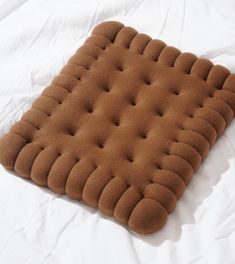 a brown cushion is laying on a white sheet