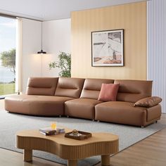 a living room with a couch, coffee table and large window overlooking the ocean in front of it