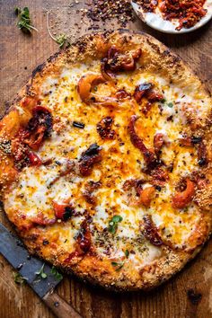 a pizza sitting on top of a wooden cutting board next to a knife and bowl