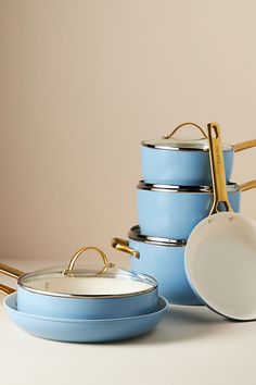 a stack of blue pots and pans with gold handles