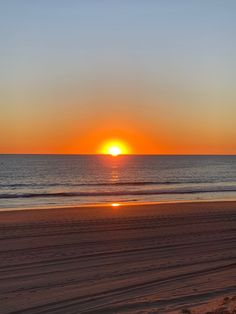 the sun is setting over the ocean and beach