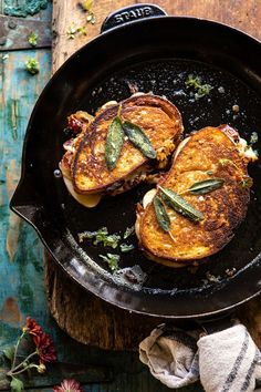 two grilled meats in a skillet on a wooden table next to flowers