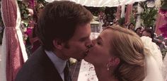 a bride and groom kissing each other in front of an outdoor wedding ceremony with pink flowers