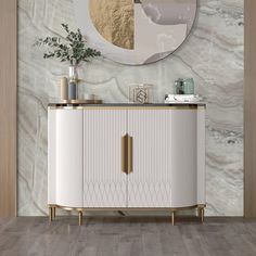 a white cabinet with gold accents in front of a marble wall and round mirror on the wall