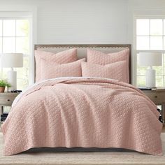 a bed with pink bedspread and pillows