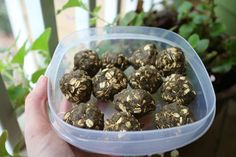 a person holding a plastic container filled with chocolate truffles on top of a wooden table