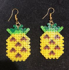 two pairs of beaded pineapple earrings on a black surface with yellow and green beads