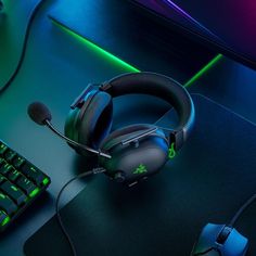 a gaming mouse, headphones and keyboard on a dark surface with neon lights in the background