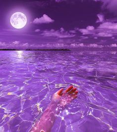 a person's hand in the water under a full moon