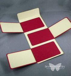 three pieces of red and white paper sitting on top of a gray surface with one piece cut out