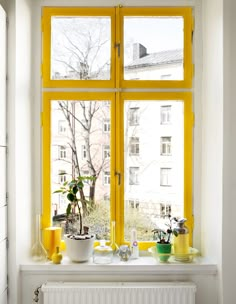 an image of a yellow window with potted plants in front of the windowsill