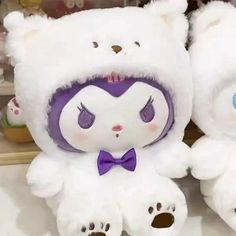 two white teddy bears with purple ears and eyes sitting next to each other on a shelf