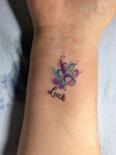 a small wrist tattoo with the word luck written on it's left arm and paw print