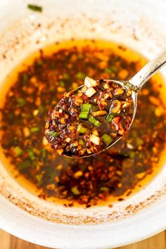 a spoon full of soup on top of a white bowl