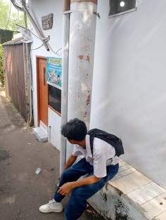 a young man sitting on the side of a building