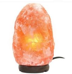 an orange himalayan salt lamp sitting on top of a wooden base