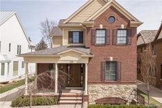 a brick house with brown shutters on the front and side windows in an urban neighborhood