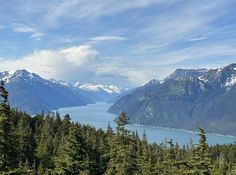 the mountains are covered in snow and pine trees, as well as some blue water