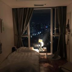 a bedroom with a large window overlooking the city at night