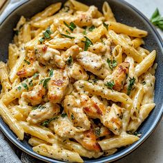 a bowl full of pasta with chicken and parsley on the side, ready to be eaten