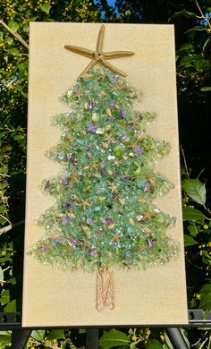 a christmas tree made out of glass beads on a piece of paper with a star hanging from the top