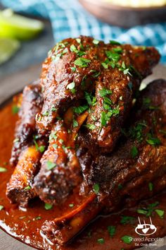 a close up of a plate of food with meat in sauce and garnished with parsley