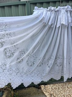 an old white lace curtain is hanging outside