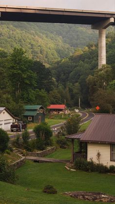 a view of a bridge over a small town in the mountains with houses and trees