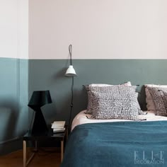 a bed with two pillows on top of it next to a night stand and lamp