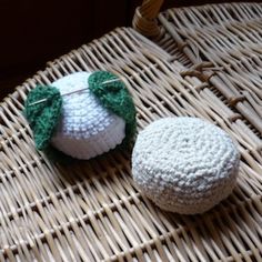 two crocheted items sitting on top of a wicker table