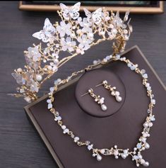 a tiara with pearls and butterflies on top of a table next to a pair of earrings