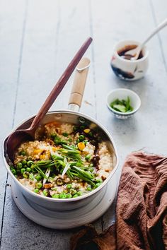 a bowl filled with rice and vegetables on top of a table next to a wooden spoon