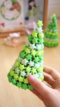 a hand is holding a small green and white christmas tree made out of star shapes