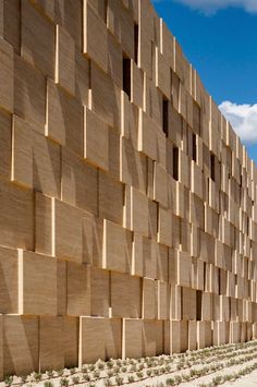 a building made out of wooden planks on the side of a road in front of a blue sky with clouds