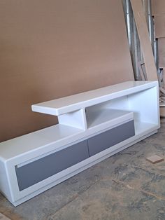 a white entertainment center sitting on top of a floor next to a pile of boxes